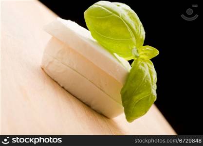 photo of sliced mozzarella with basil leaf on wooden cutting board