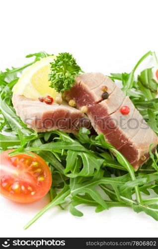 photo of sliced Tuna Steak with arugula salad on white isolated background