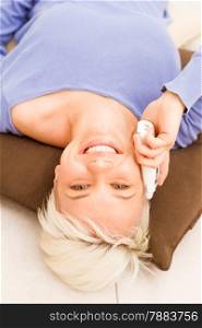 photo of smiling blonde woman lying on the floor while speaking at phone