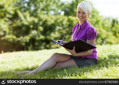 Photo of smiling blonde woman sitting in a park