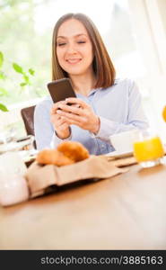 Photo of smiling brunette businesswoman having breakfast while checking her emails