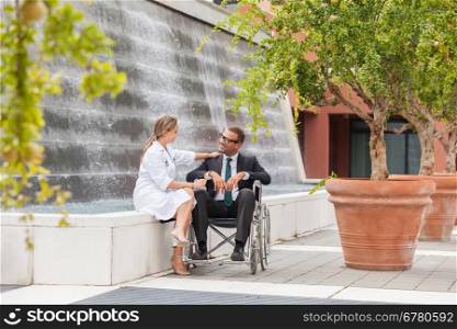 Photo of smiling businessman on wheelchair looking towards his doctor