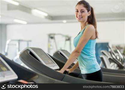 Photo of smiling caucasian brunette running on a treadmill in gym