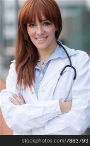 photo of smiling caucasian female doctor standing next to window