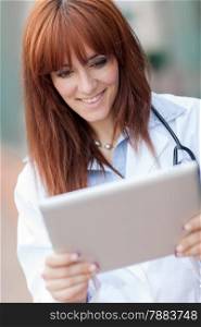 photo of smiling female doctor looking at tablet pc