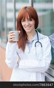 photo of smiling female doctor standing outside and having cappuccino