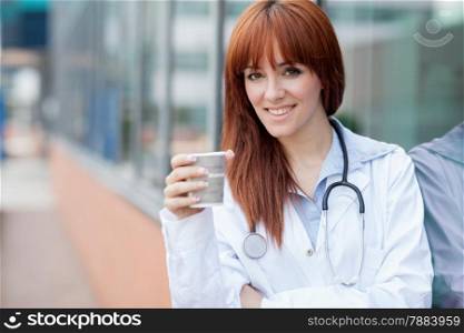 photo of smiling female doctor standing outside and having cappuccino