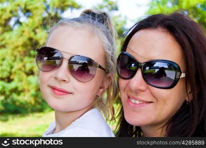 Photo of smiling mother and daughter in sunglasses