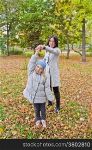 Photo of smiling mother and daughter play in autumn
