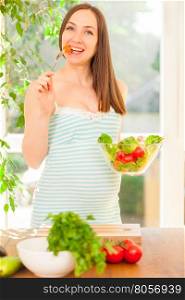 Photo of smiling pregnant woman eating salad