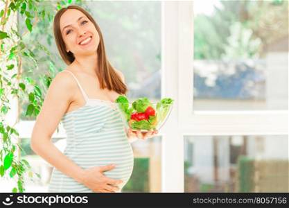 Photo of smiling pregnant woman eating salad