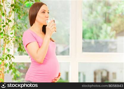 Photo of smiling pregnant woman holding a glass of water