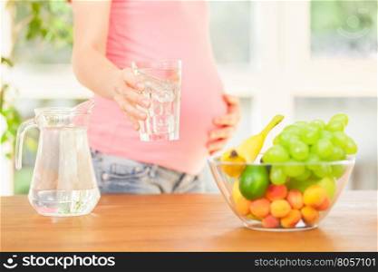 Photo of smiling pregnant woman holding a glass of water