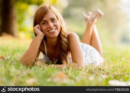Photo of smiling woman laying in a grass field while looking towards the camera