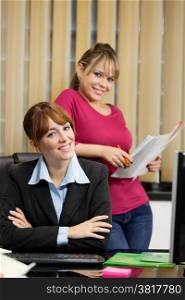 photo of smiling young businesswoman and her female assistant in the office