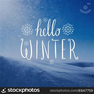Photo of snowstorm in sunny day with Hello Winter lettering. Winter holidays card.. Photo of snowstorm in sunny day with Hello Winter lettering.