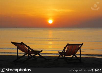 photo of sunbed on the beach with sunrise background