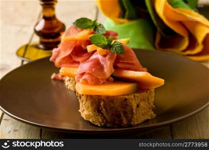 photo of tasty bread slices with bacon and melon