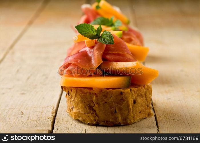 photo of tasty bread slices with bacon and melon