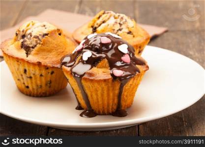 Photo of tasty cupcakes with chocolate over wooden table