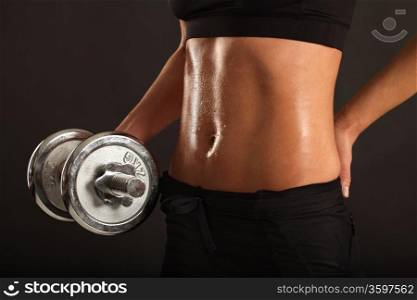 Photo of the stomach from a sweaty slim female lifting a dumbbell.