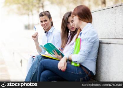 Photo of three female students sitting on a bench with notebooks
