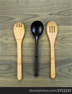 Photo of three kitchen spoons, two of them wooden, on aged white oak boards
