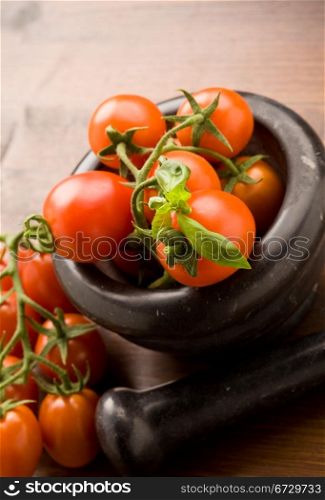 photo of tomatoes inside a black mortar ready to be smashed for preparing tomatoe sauce