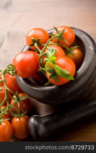 photo of tomatoes inside a black mortar ready to be smashed for preparing tomatoe sauce