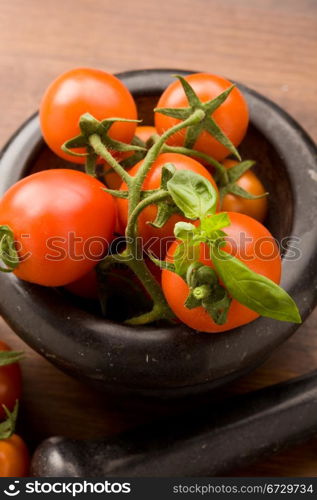 photo of tomatoes inside a black mortar ready to be smashed for preparing tomatoe sauce