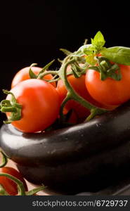 photo of tomatoes inside a black mortar ready to be smashed for preparing tomatoe sauce