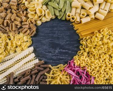 Photo of twelve different pasta types arranged on a slate surface as a frame.