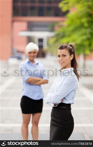 Photo of two businesswoman standing next to each other outdoors