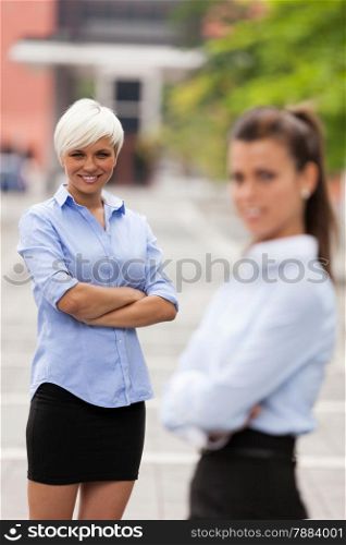 Photo of two businesswoman standing next to each other outdoors
