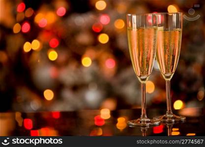 photo of two champagner glasses on glass table with bokeh background