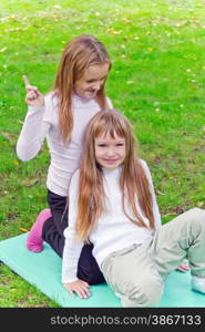 Photo of two girls sitting on grass in summer