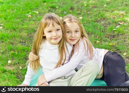 Photo of two girls sitting on grass in summer