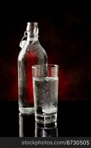 photo of water glass and bottle standing on black glass table