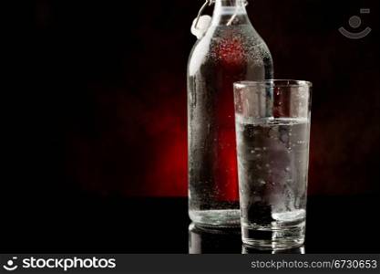 photo of water glass and bottle standing on black glass table