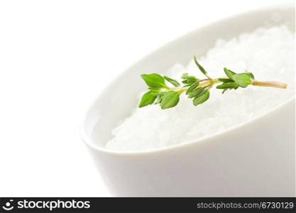 photo of white raw sea salt with parsley on white isolated background
