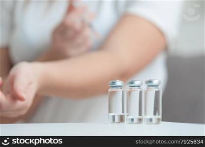 Photo of woman doing injection behind empty ampules