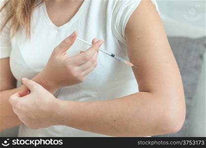 Photo of woman doing injection with syringe in hand