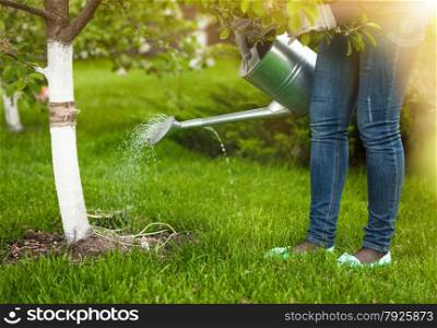Photo of woman pouring water of watering can on tree at garden