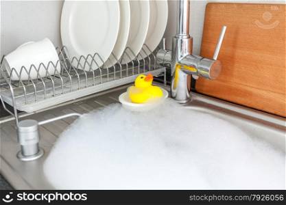 Photo of yellow rubber duck in foamy kitchen sink
