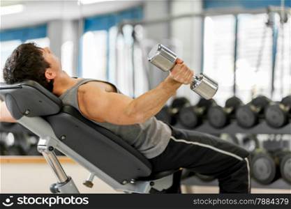 Photo of young caucasian man working out his arms with dumbbells
