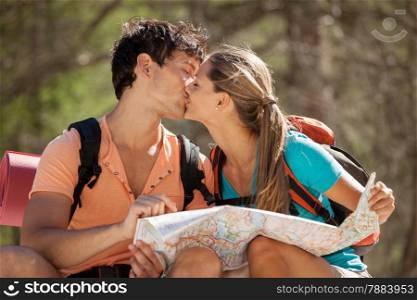 Photo of young couple sitting on a big rock in the mountains and kisses each other