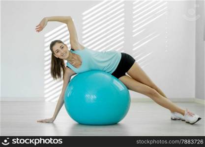 Photo of young smiling woman doing workout with a gym ball