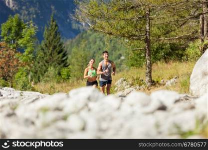 Photo of young sporty couple doing running in the mountains