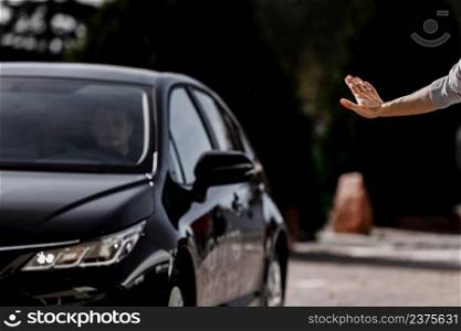 Photo of young woman stopping luxury black car on street. A girl waves her hand on the street. Photo of young woman stopping luxury black car on street. A girl waves her hand on the street.
