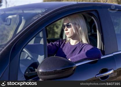 Photo portrait woman wearing sunglasses keeping steering wheel in the car